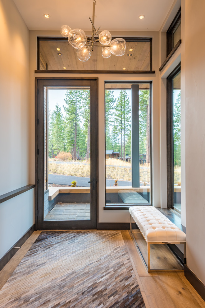Diseño de distribuidor minimalista de tamaño medio con paredes grises, suelo de madera en tonos medios, puerta simple, puerta de madera oscura y suelo marrón