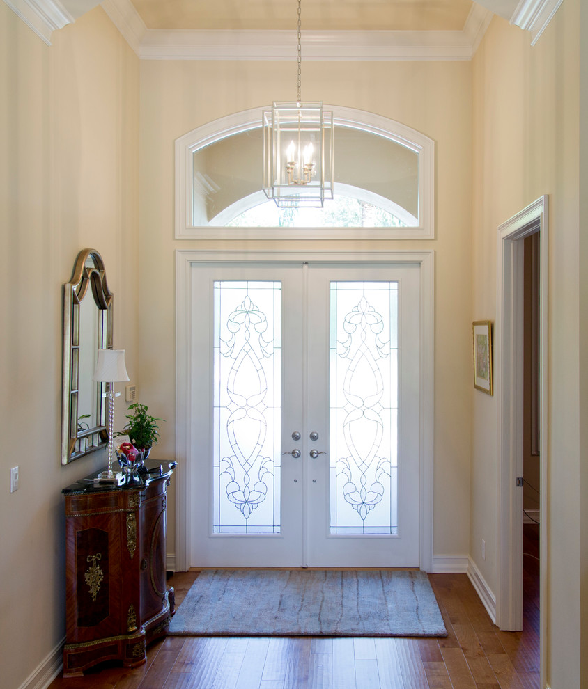 На фото: входная дверь среднего размера в классическом стиле с желтыми стенами, паркетным полом среднего тона, двустворчатой входной дверью и белой входной дверью с