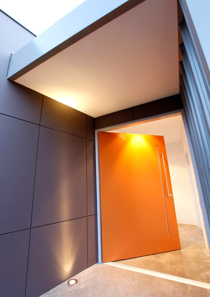 Trendy concrete floor pivot front door photo in Perth with an orange front door