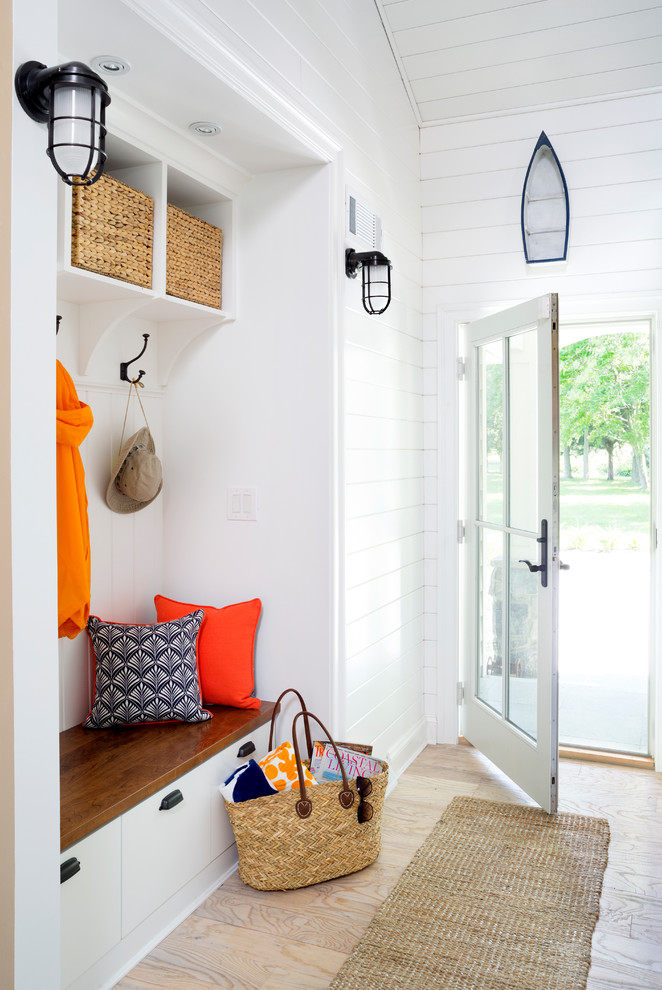 Example of a mid-sized beach style light wood floor entryway design in DC Metro with white walls and a glass front door