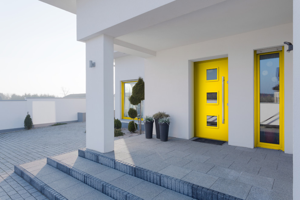 На фото: входная дверь в стиле модернизм с белыми стенами, одностворчатой входной дверью и желтой входной дверью