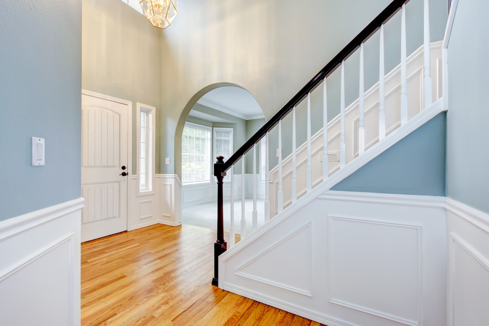Ispirazione per un grande ingresso o corridoio con pareti blu, pavimento in legno massello medio, una porta singola e una porta bianca