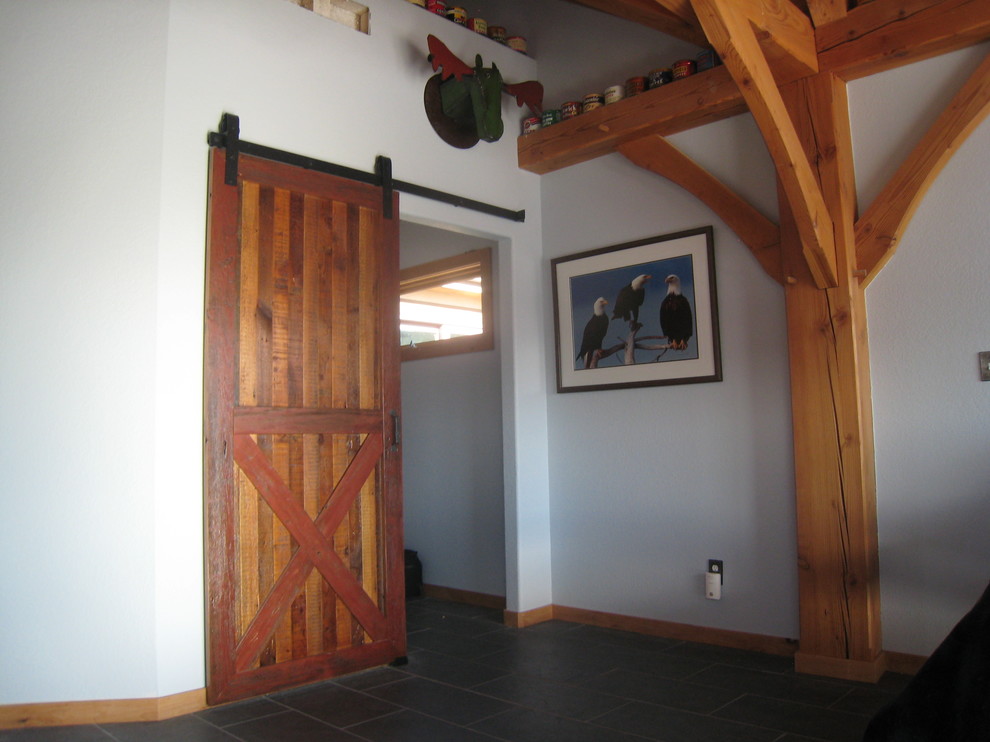 Diseño de entrada rústica de tamaño medio con paredes blancas, puerta de madera en tonos medios, suelo gris y suelo de pizarra
