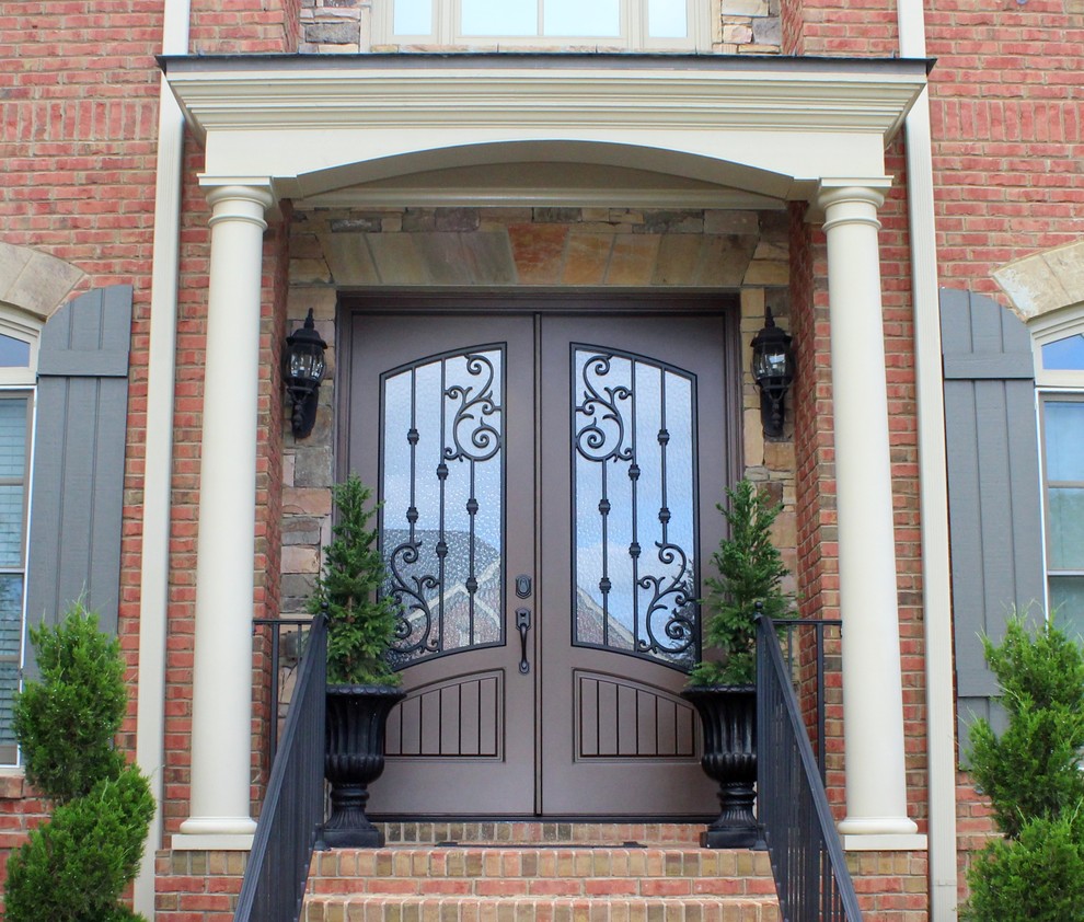 Foto de puerta principal clásica grande con paredes beige, suelo de ladrillo, puerta doble, puerta marrón y suelo rojo