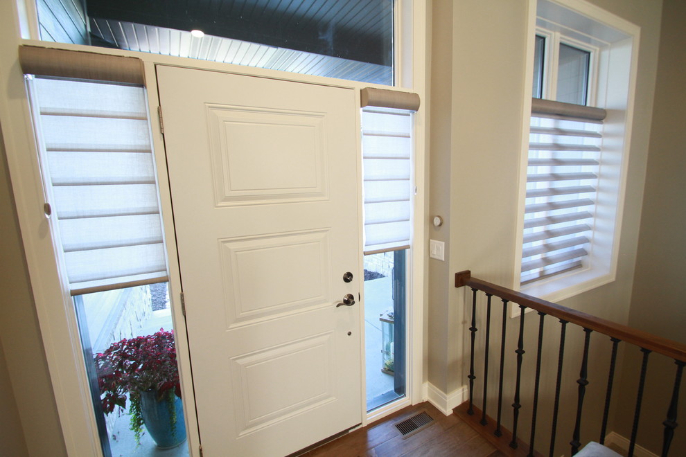 Ispirazione per una piccola porta d'ingresso tradizionale con pareti grigie, pavimento in legno massello medio, una porta singola, una porta bianca e pavimento marrone