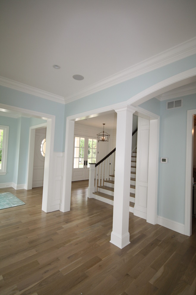 Idee per un ingresso classico di medie dimensioni con pareti blu, parquet chiaro, una porta singola, una porta bianca e pavimento marrone
