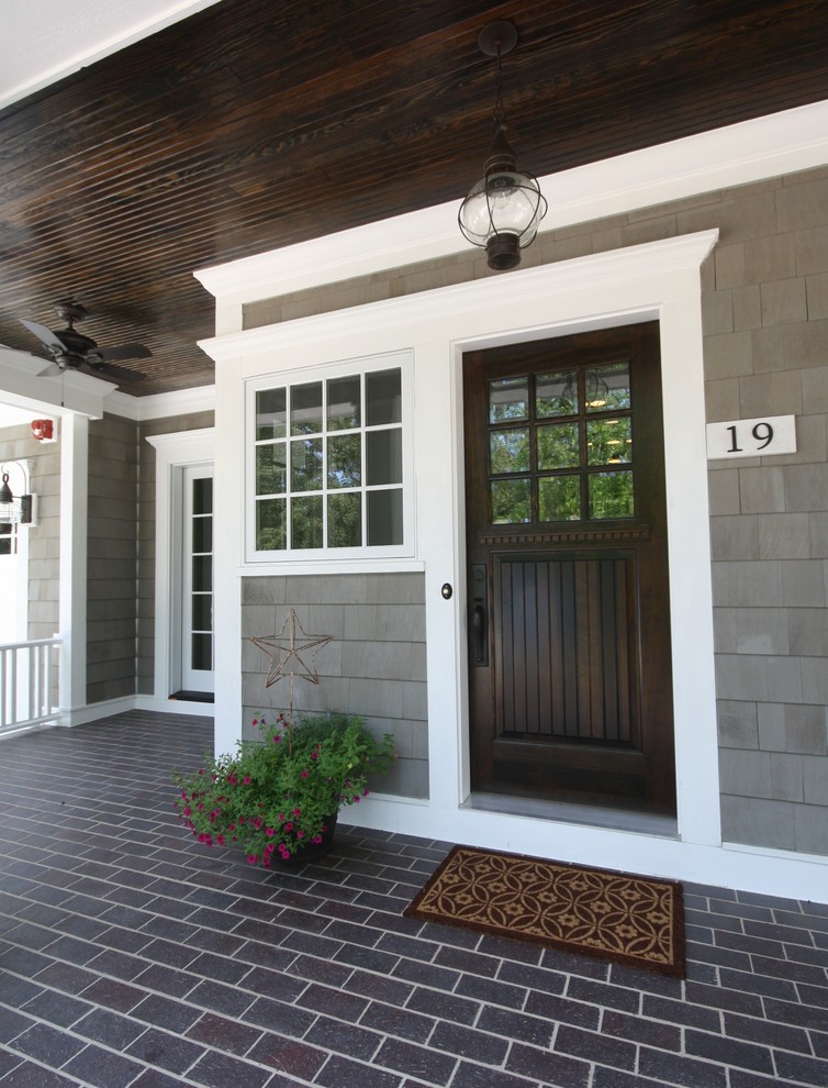 This is an example of a nautical entrance in Chicago with a single front door, a dark wood front door and feature lighting.