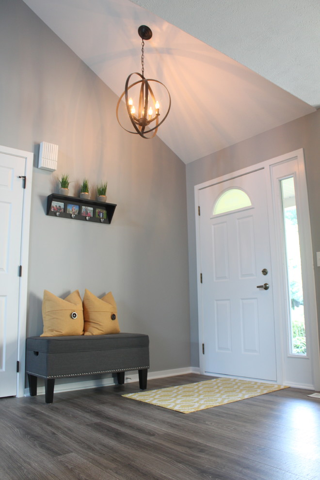 Example of a mid-sized trendy medium tone wood floor entryway design in Grand Rapids with multicolored walls and a white front door