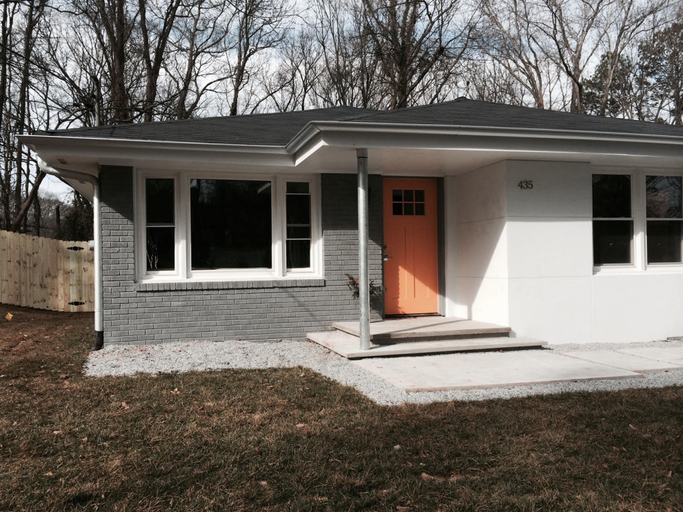 Kleine Klassische Haustür mit weißer Wandfarbe, Betonboden, Einzeltür, oranger Haustür, grauem Boden und Ziegelwänden in Atlanta
