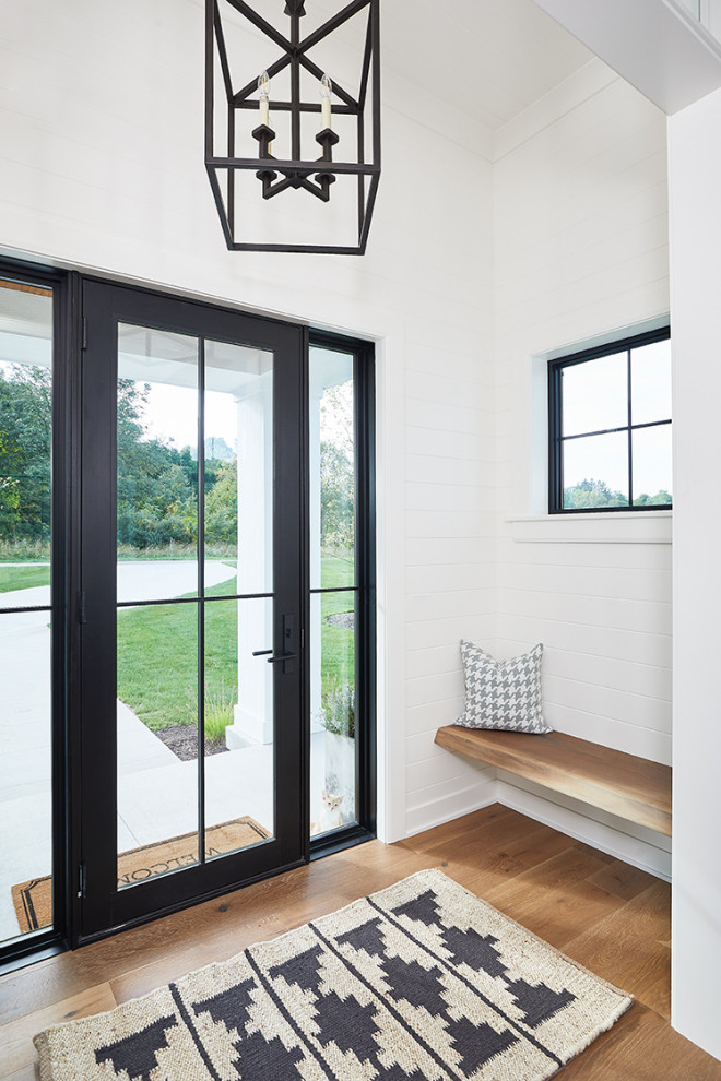 Стильный дизайн: вестибюль с белыми стенами, светлым паркетным полом, одностворчатой входной дверью, черной входной дверью и коричневым полом - последний тренд