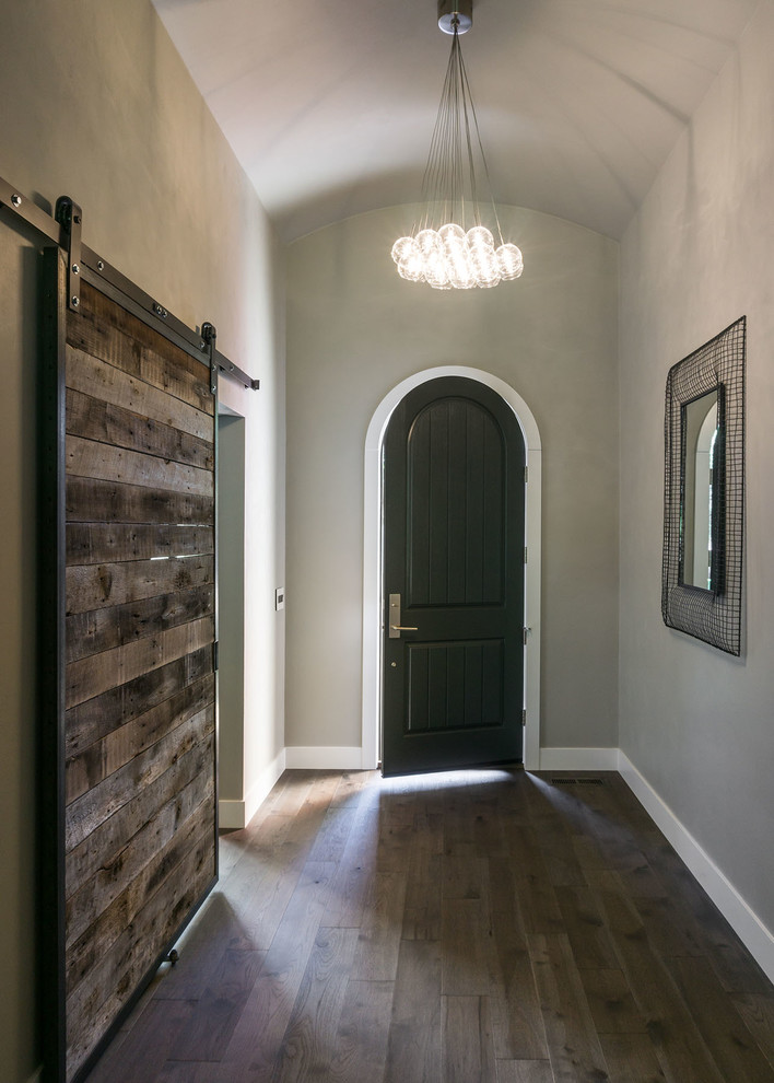 Cette photo montre un grand hall d'entrée tendance avec un mur beige, un sol en bois brun, une porte simple et une porte noire.