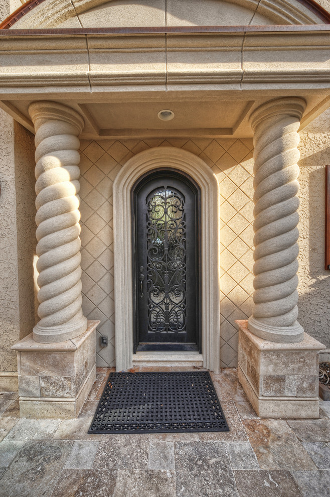 Immagine di un ingresso o corridoio mediterraneo con pareti bianche, pavimento in granito, una porta singola e una porta in metallo