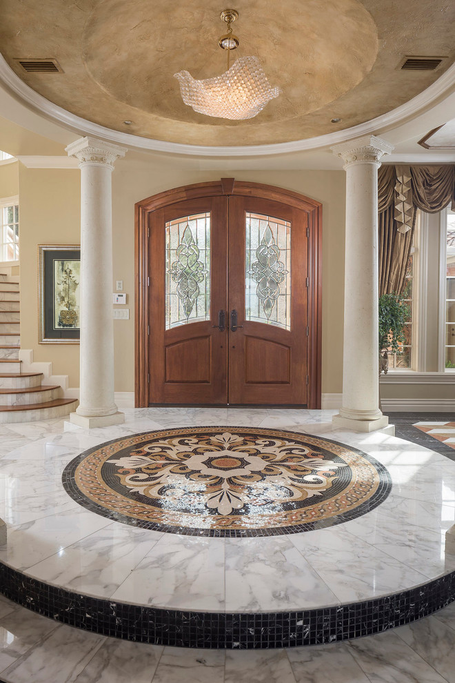 Foto di un ampio ingresso mediterraneo con pareti beige, pavimento in marmo, una porta a due ante, una porta in legno bruno e pavimento multicolore