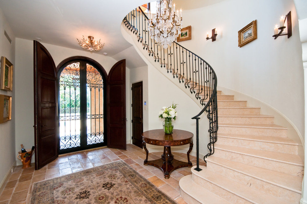 Inspiration for a large mediterranean ceramic tile entryway remodel in Miami with a dark wood front door and white walls