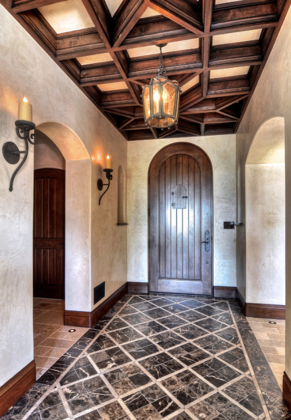 ロサンゼルスにある高級な中くらいな地中海スタイルのおしゃれな玄関ロビー (茶色い壁、大理石の床、濃色木目調のドア、黒い床) の写真