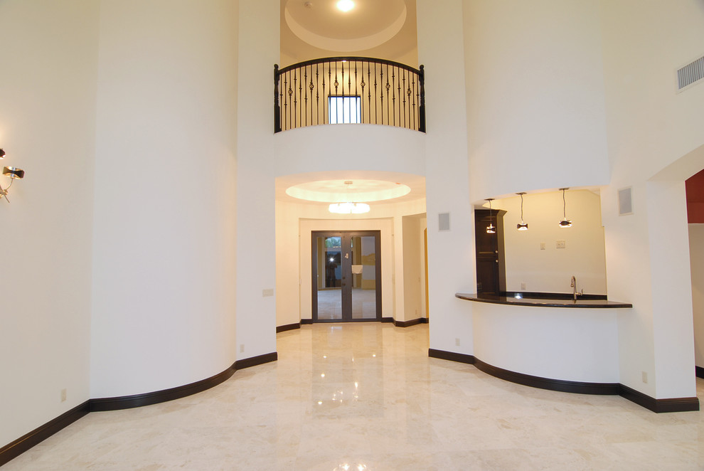 Ejemplo de puerta principal mediterránea grande con paredes blancas, suelo de mármol y puerta de vidrio