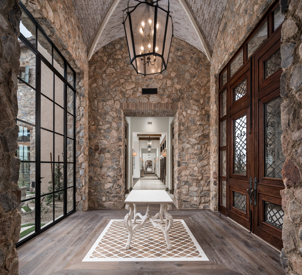 Idee per un ingresso mediterraneo con pareti grigie, pavimento in legno massello medio, una porta a due ante, una porta in legno bruno e pavimento marrone