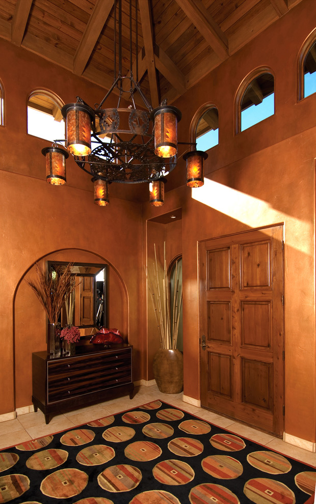Пример оригинального дизайна: фойе среднего размера в средиземноморском стиле с оранжевыми стенами, одностворчатой входной дверью, входной дверью из дерева среднего тона и полом из травертина