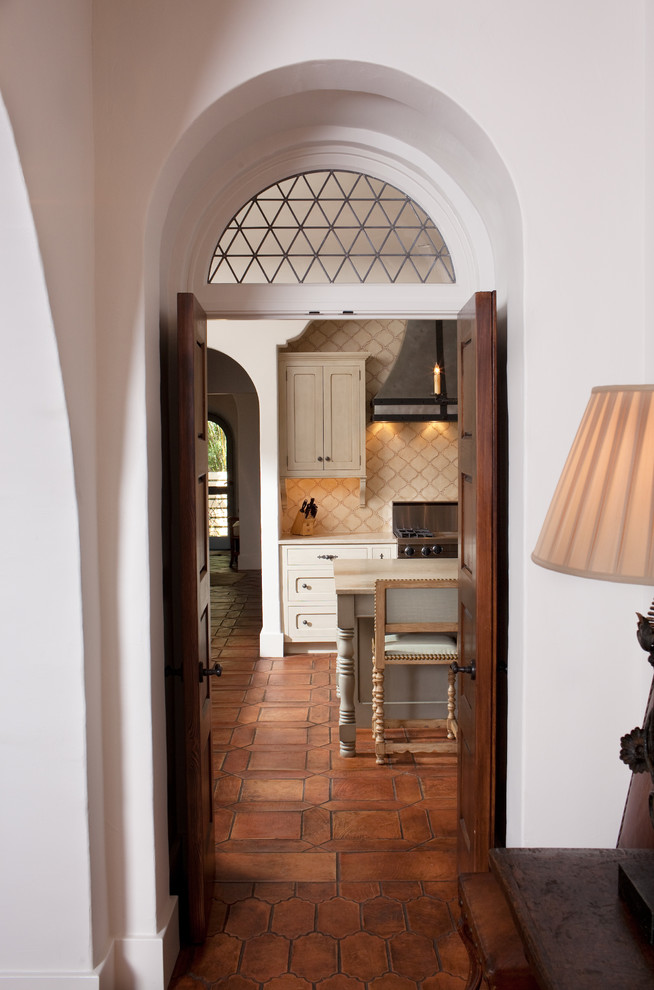 他の地域にある地中海スタイルのおしゃれな玄関 (濃色木目調のドア、テラコッタタイルの床) の写真