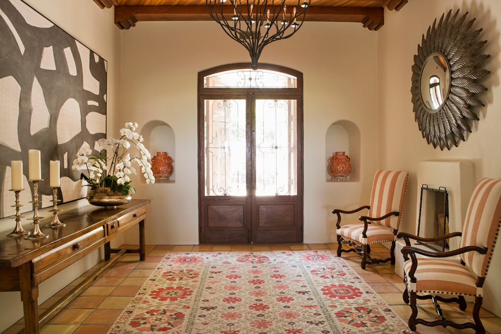 Immagine di un ingresso o corridoio mediterraneo con pareti beige, pavimento in terracotta, una porta a due ante e una porta in vetro