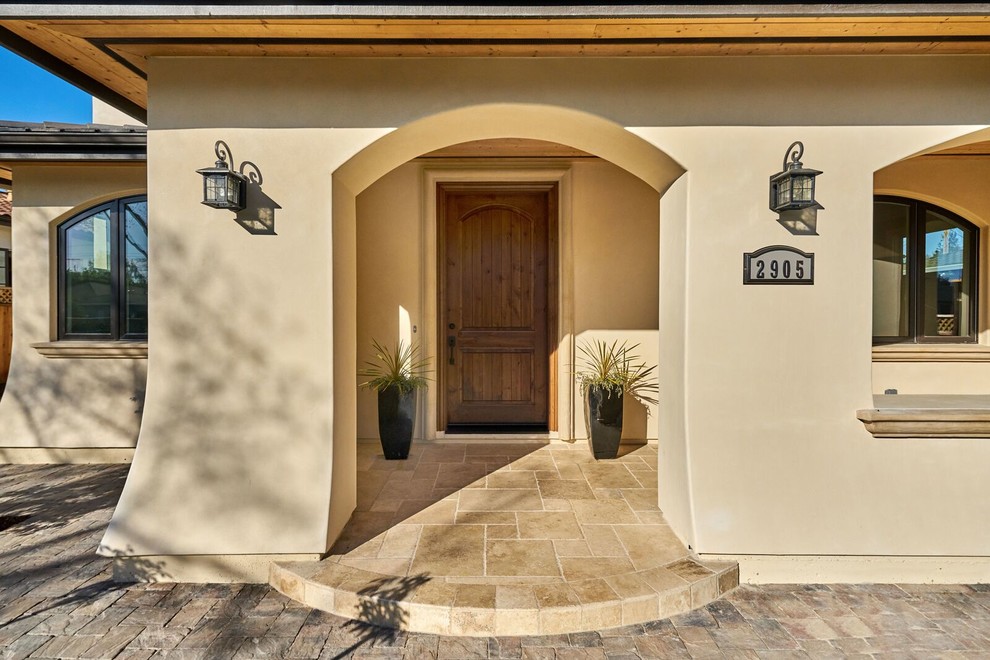 Inspiration pour une porte d'entrée méditerranéenne avec un mur beige, une porte simple, une porte en bois brun et un sol beige.