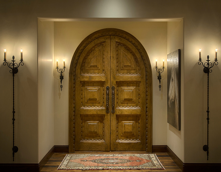 Cette photo montre une grande porte d'entrée méditerranéenne avec une porte double, une porte en bois brun, un mur beige et parquet foncé.