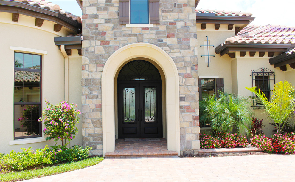 Example of a large tuscan entryway design in Miami with a metal front door