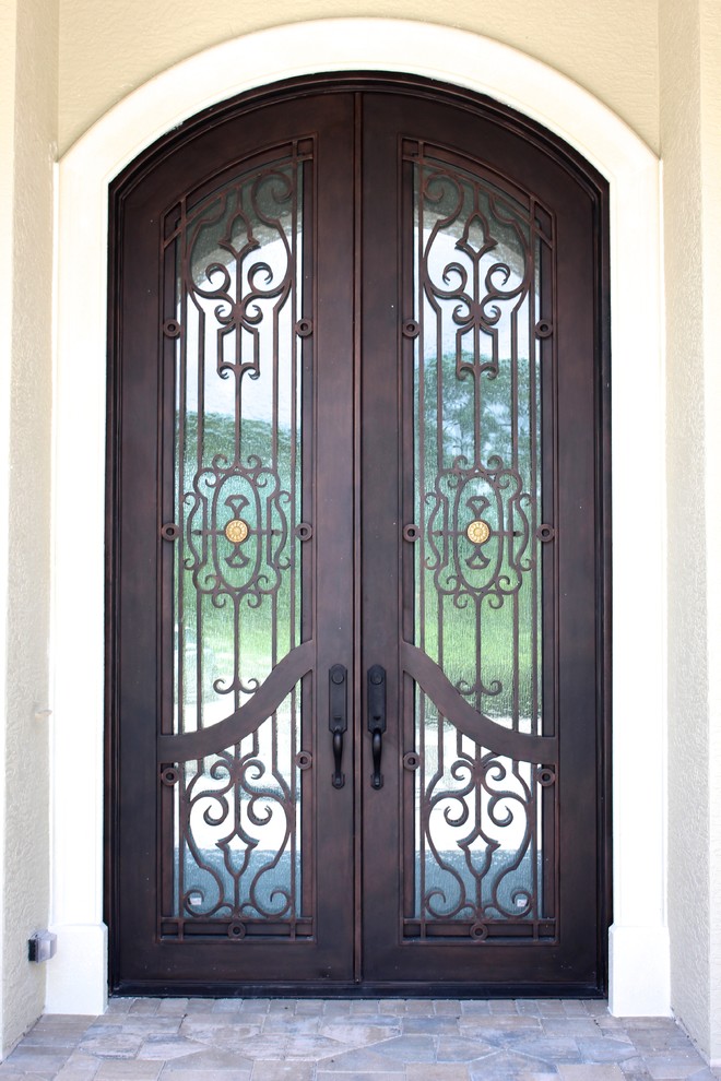 Immagine di una grande porta d'ingresso mediterranea con una porta a due ante e una porta in metallo