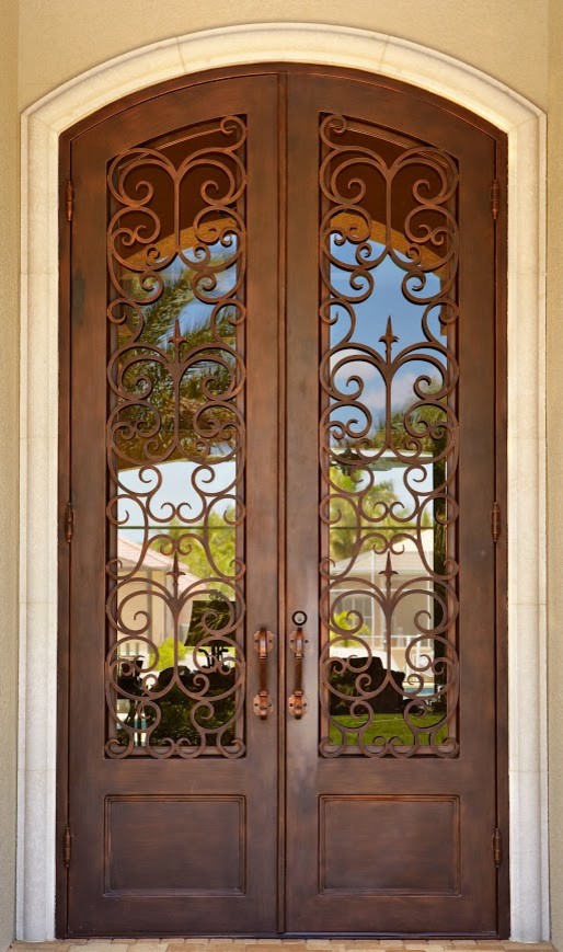 Cette image montre une grande porte d'entrée méditerranéenne avec une porte double et une porte métallisée.