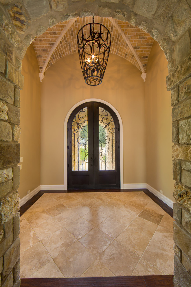 Пример оригинального дизайна: большая входная дверь в средиземноморском стиле с бежевыми стенами, двустворчатой входной дверью, черной входной дверью и полом из травертина