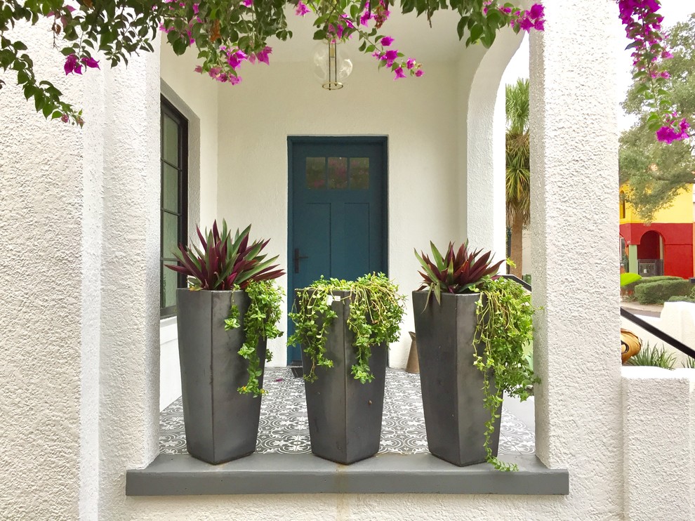 Пример оригинального дизайна: маленькая входная дверь в средиземноморском стиле с белыми стенами, одностворчатой входной дверью и разноцветным полом для на участке и в саду