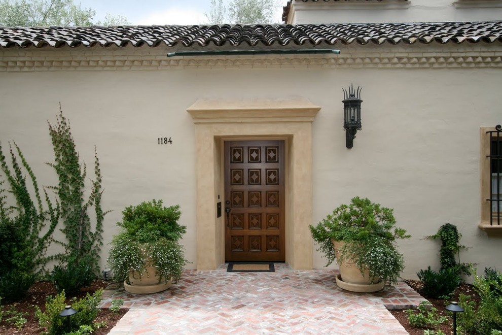 На фото: входная дверь в средиземноморском стиле с одностворчатой входной дверью и входной дверью из темного дерева