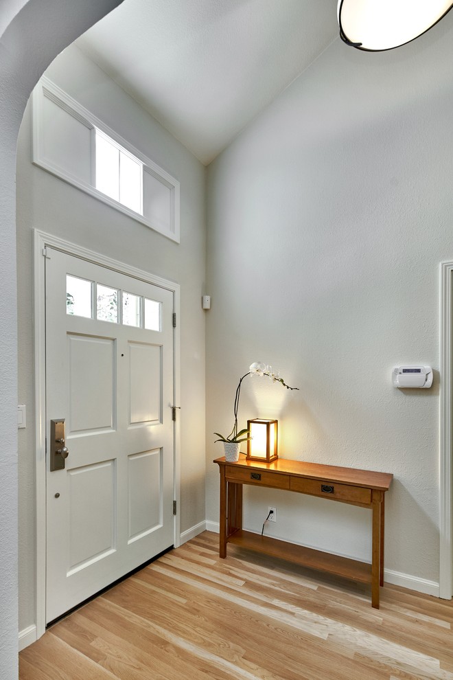Foto di un ingresso chic di medie dimensioni con pareti grigie, parquet chiaro, una porta singola, una porta bianca e soffitto a volta