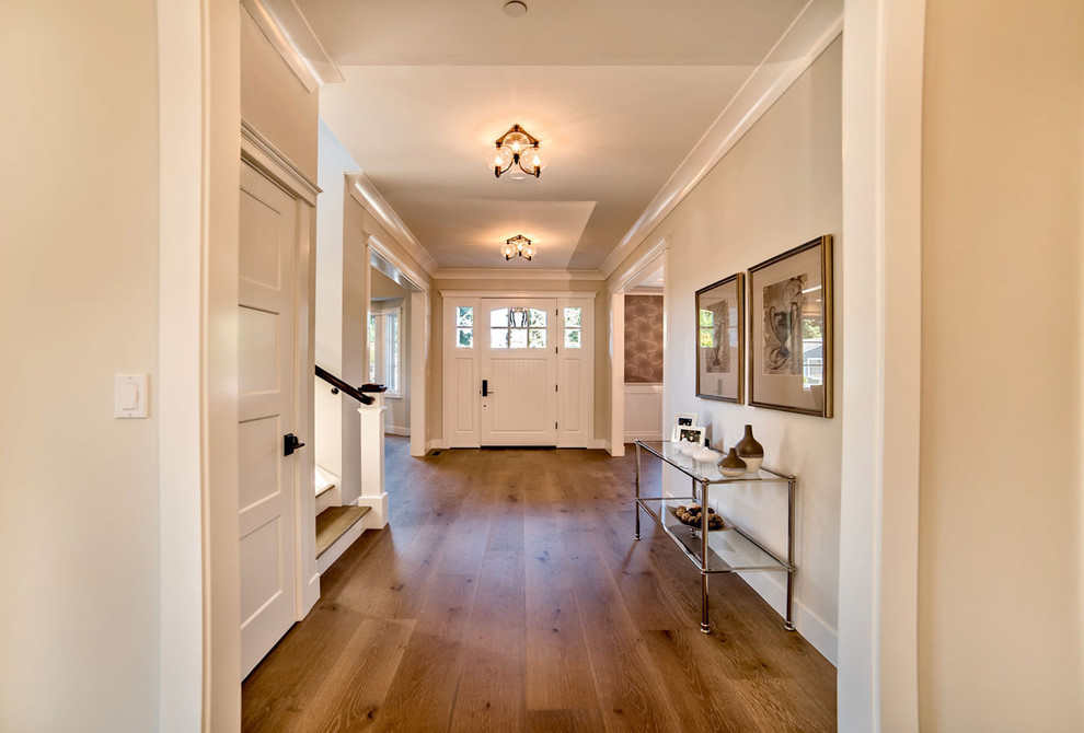 Idées déco pour une entrée classique avec un couloir, un mur beige, un sol en bois brun, une porte simple, une porte blanche et un sol marron.
