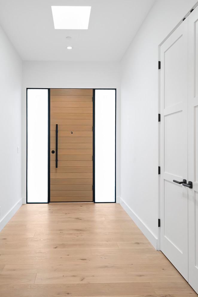 Пример оригинального дизайна: входная дверь среднего размера в стиле модернизм с белыми стенами, светлым паркетным полом, одностворчатой входной дверью, входной дверью из светлого дерева и коричневым полом