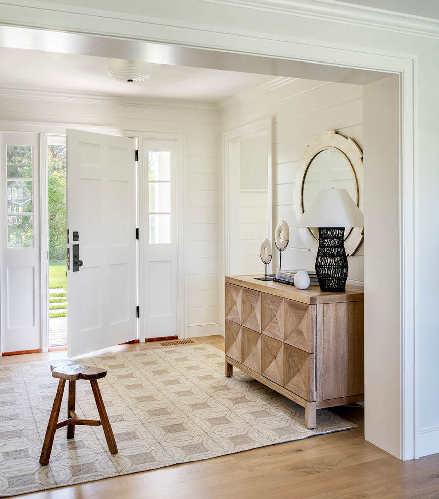 Imagen de entrada marinera con paredes blancas, suelo de madera en tonos medios, puerta simple, puerta blanca, suelo marrón y machihembrado