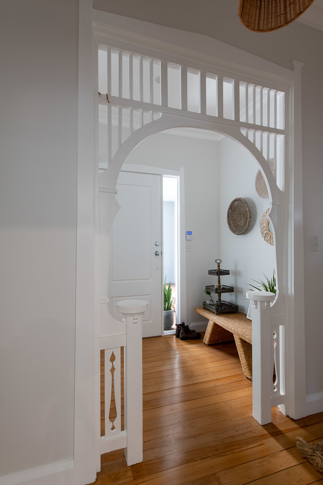 ニューカッスルにあるトランジショナルスタイルのおしゃれな玄関ロビー (白い壁、無垢フローリング、白いドア、茶色い床) の写真