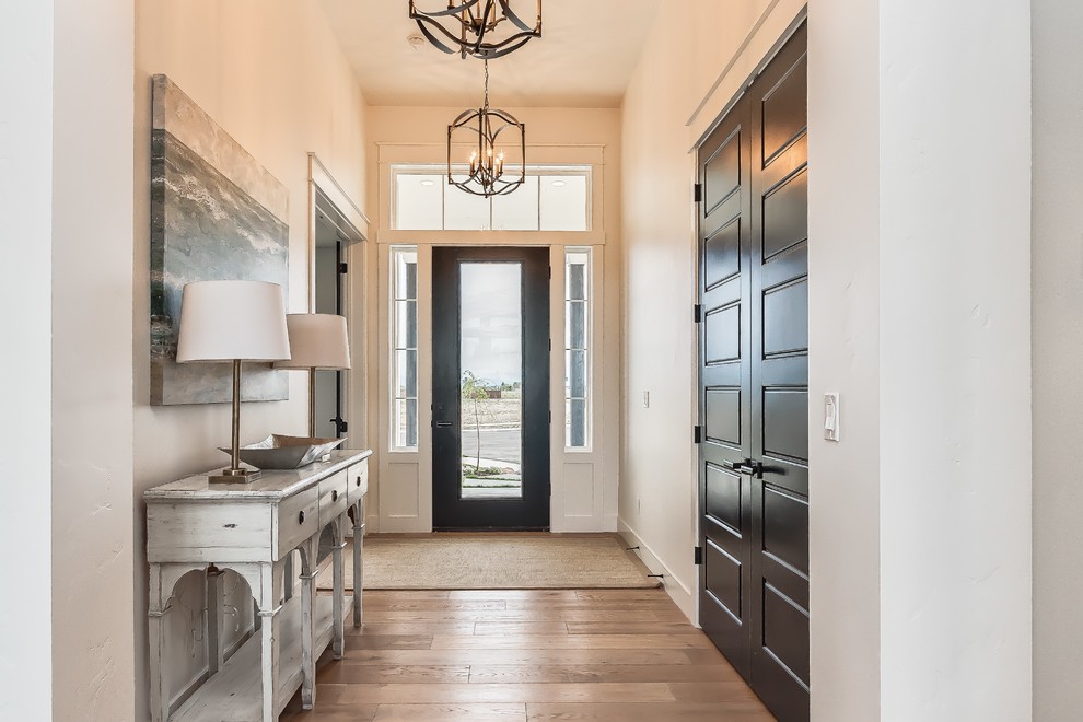 Entryway - cottage light wood floor entryway idea in Boise with white walls and a black front door