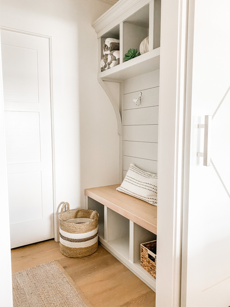 Exemple d'une petite entrée chic avec un vestiaire, un mur blanc, parquet clair, une porte simple, une porte blanche, un sol beige et du lambris de bois.
