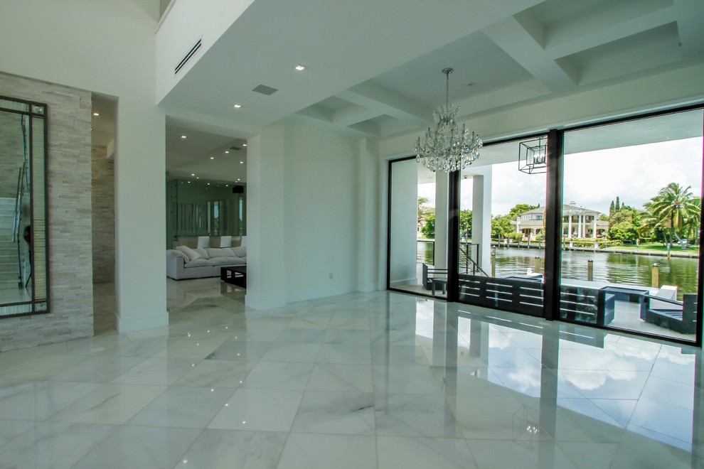 マイアミにある広いモダンスタイルのおしゃれな玄関ロビー (白い壁、大理石の床、ガラスドア、白い床) の写真