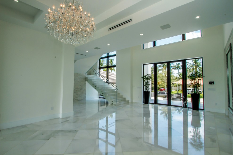 Idee per un grande ingresso minimalista con pareti bianche, pavimento in marmo, una porta a due ante, una porta in vetro e pavimento bianco