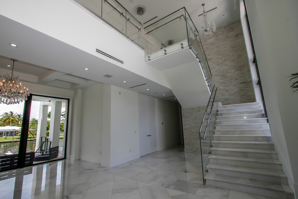 Idée de décoration pour un grand hall d'entrée minimaliste avec un mur blanc, un sol en marbre, une porte double, une porte en verre et un sol blanc.