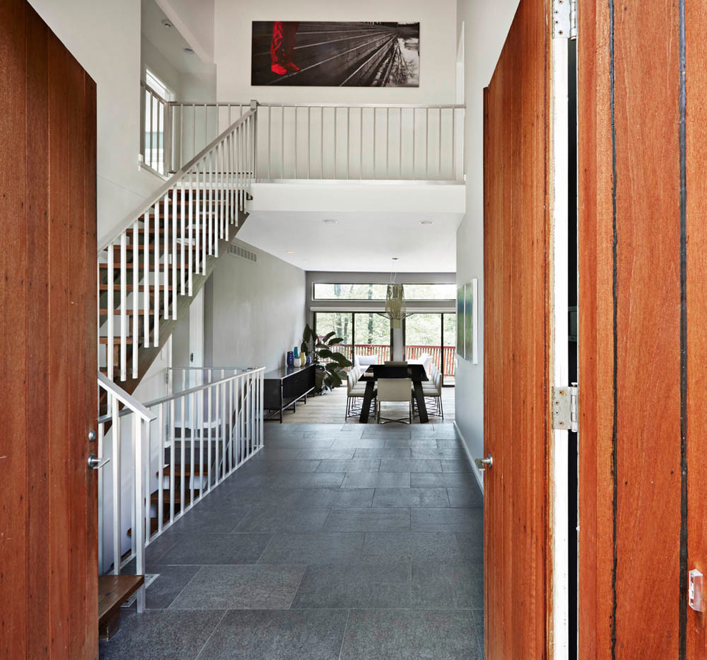 Immagine di un ingresso o corridoio minimal con pareti grigie, pavimento con piastrelle in ceramica, una porta a due ante e una porta in legno bruno