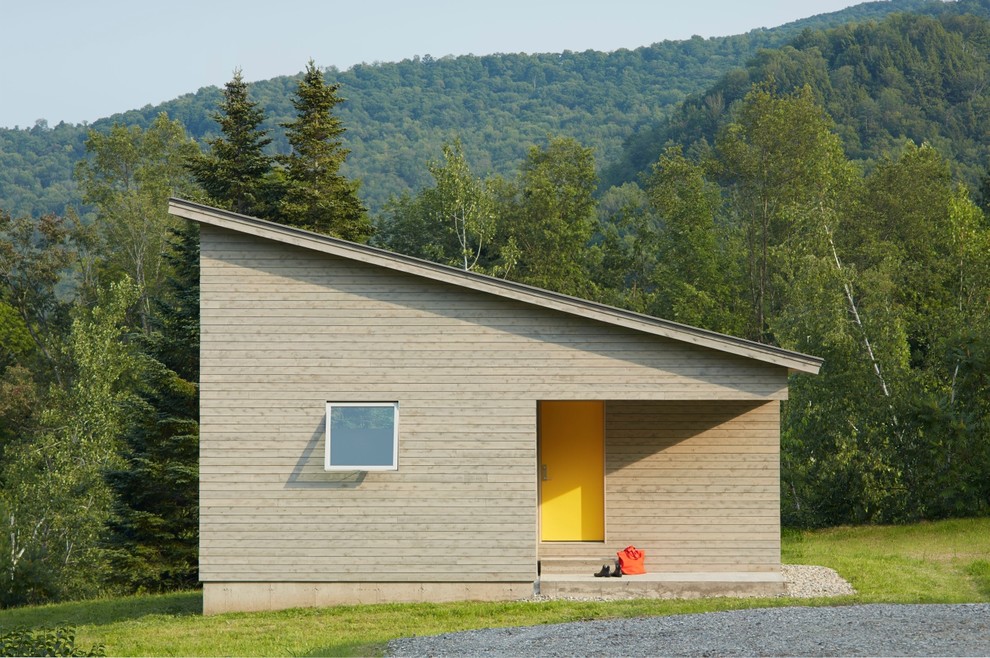 На фото: маленькая входная дверь в стиле модернизм с серыми стенами, бетонным полом, одностворчатой входной дверью и желтой входной дверью для на участке и в саду