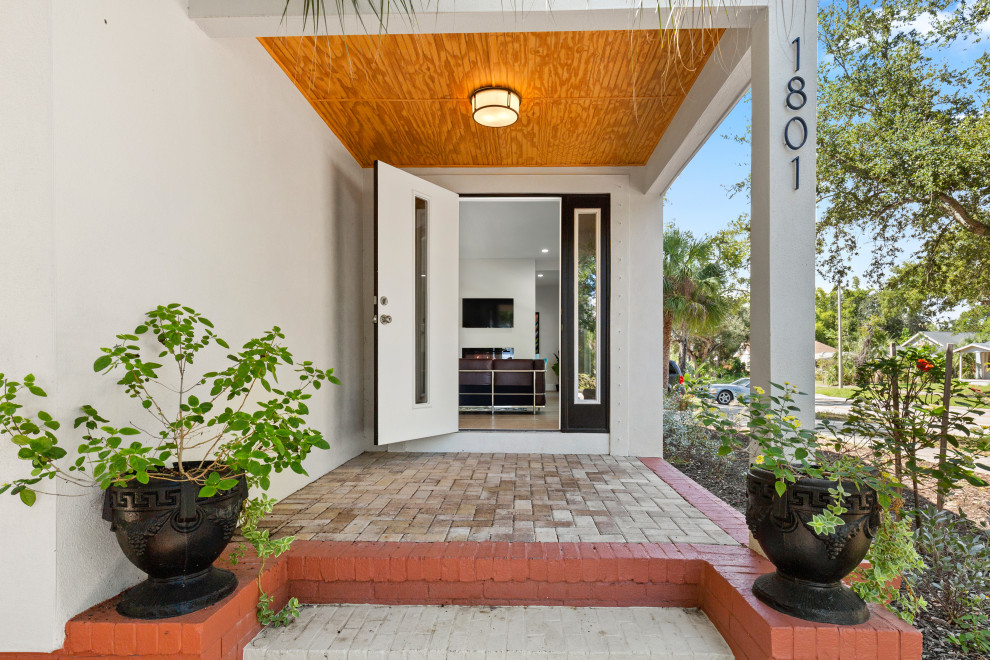 This is an example of a small midcentury front door in Tampa with white walls, brick flooring, a single front door, a black front door, multi-coloured floors and a wood ceiling.
