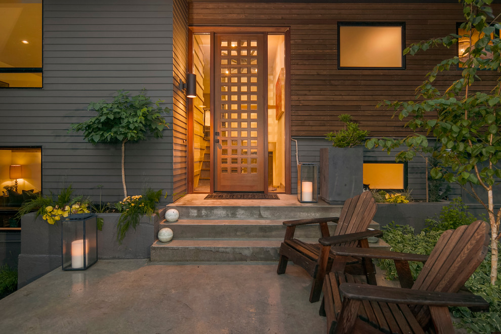 Idee per una porta d'ingresso minimalista di medie dimensioni con pareti grigie, pavimento in cemento, una porta singola e una porta in legno bruno