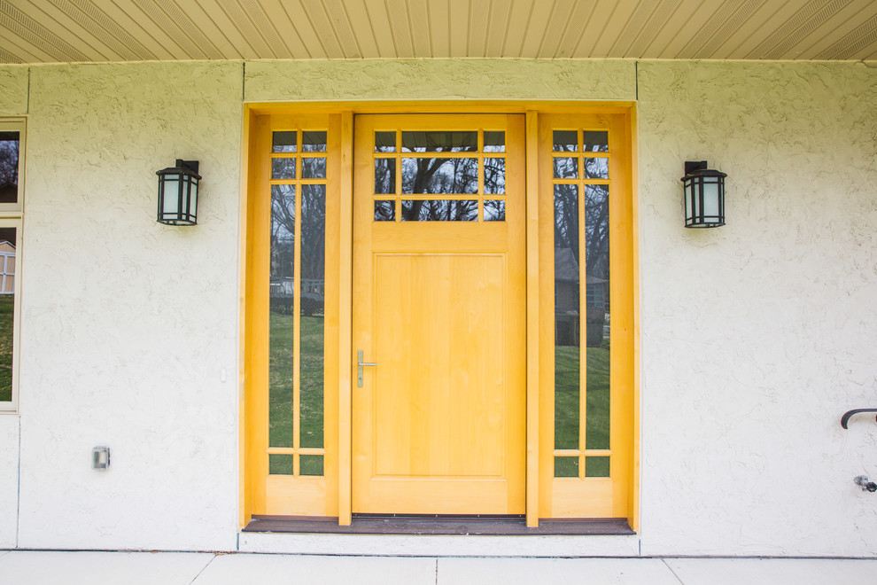 Réalisation d'une grande porte d'entrée craftsman avec une porte simple et une porte jaune.