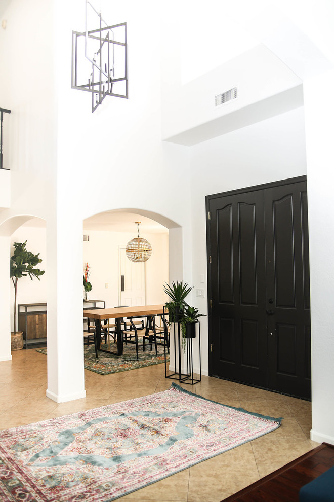 フェニックスにある高級な広いミッドセンチュリースタイルのおしゃれな玄関ロビー (白い壁、トラバーチンの床、黒いドア、ベージュの床) の写真