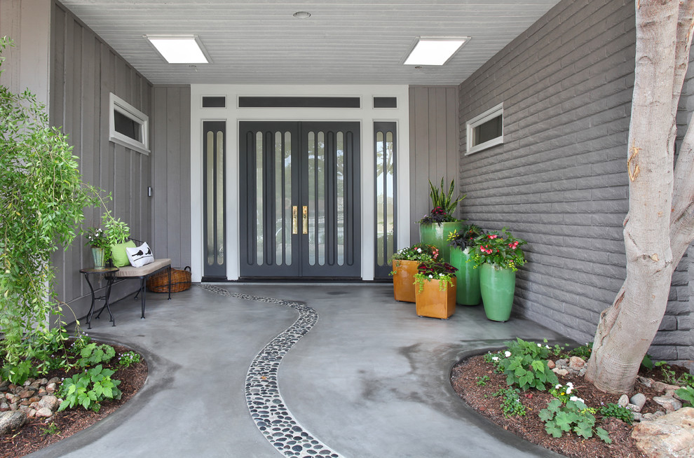 Cette photo montre une porte d'entrée rétro de taille moyenne avec un mur gris, sol en béton ciré et une porte double.