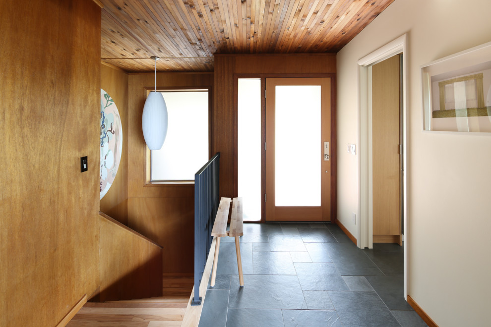 シアトルにある小さなミッドセンチュリースタイルのおしゃれな玄関ドア (白い壁、スレートの床、淡色木目調のドア、グレーの床) の写真